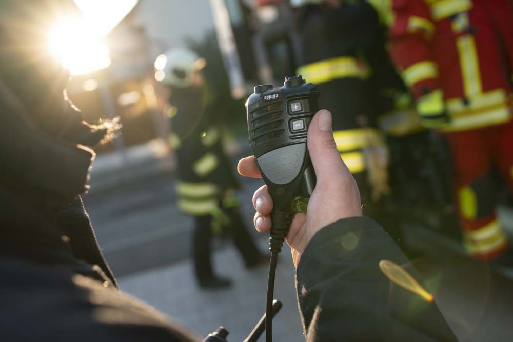 Ein Feuerwehrmensch hält ein Funkgerät in der Hand.